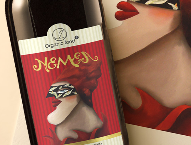 Artistic Nemea wine bottle label featuring gold custom typography and a surreal illustration of a masked woman.